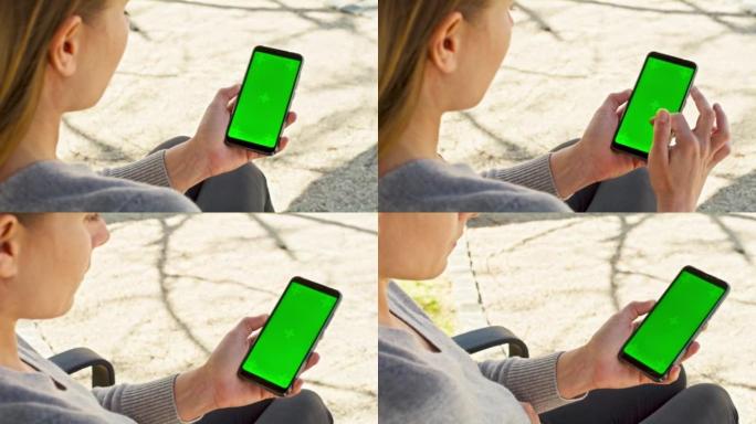 女人坐在公园的长椅上，看着智能手机上的东西