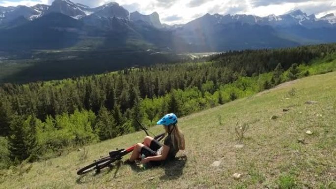 女性山地自行车手在高山草甸放松，骑自行车