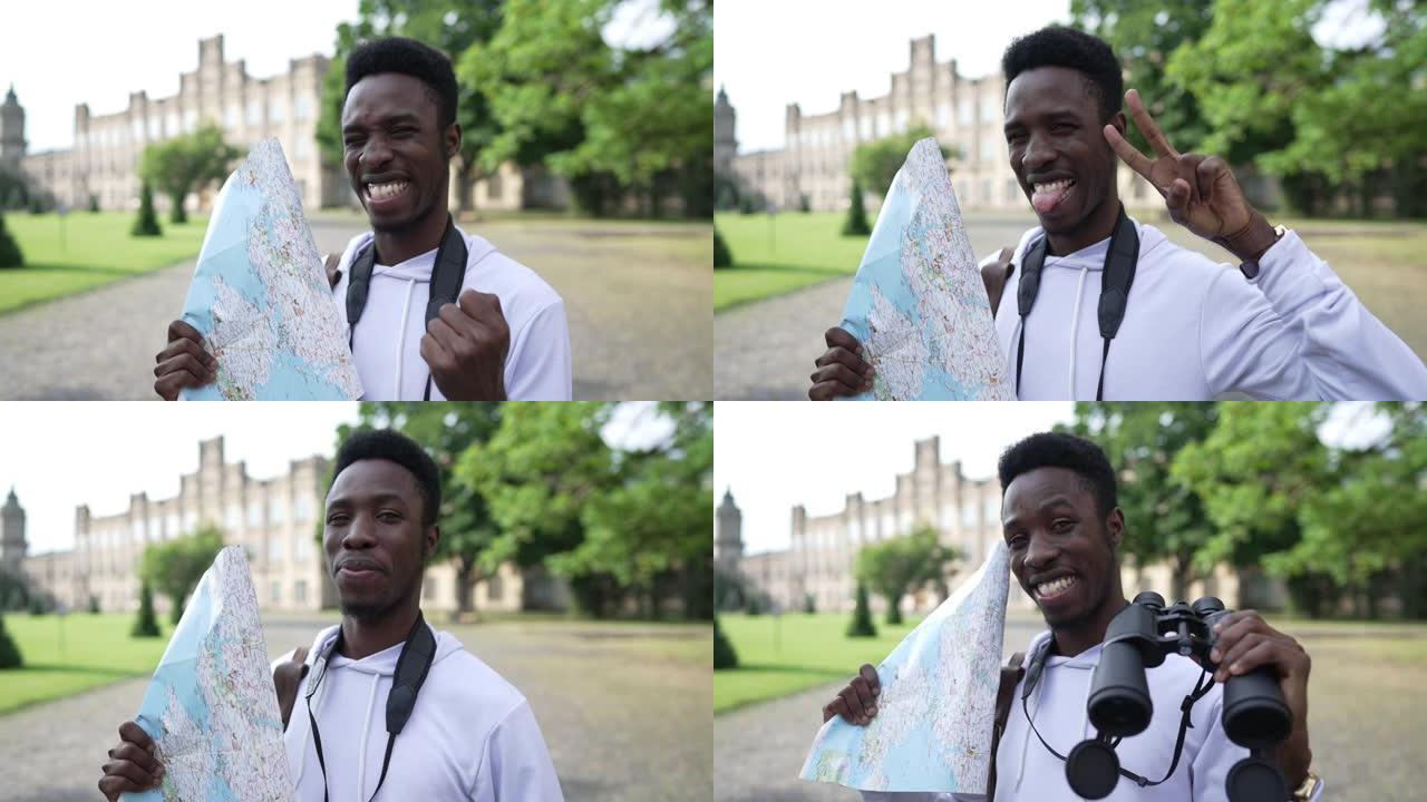 快乐的非裔美国游客在户外的欧洲小镇用纸质地图和双筒望远镜摆姿势。快乐兴奋的英俊年轻人看着相机微笑示意