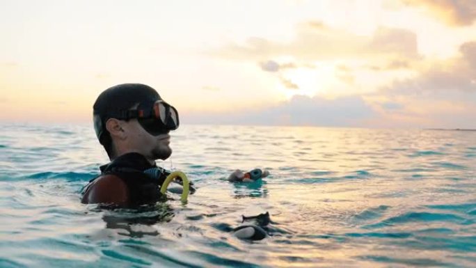 一名潜水员从水中出来并在日落时取下面具的特写镜头
