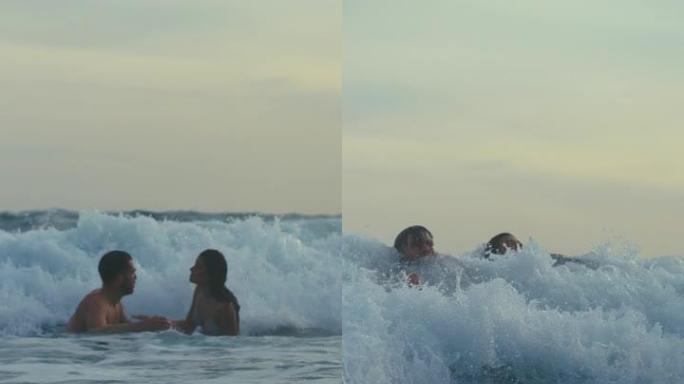 海滩上的浪漫情侣。在海中玩耍在海浪中游泳在海浪下潜水垂直视频