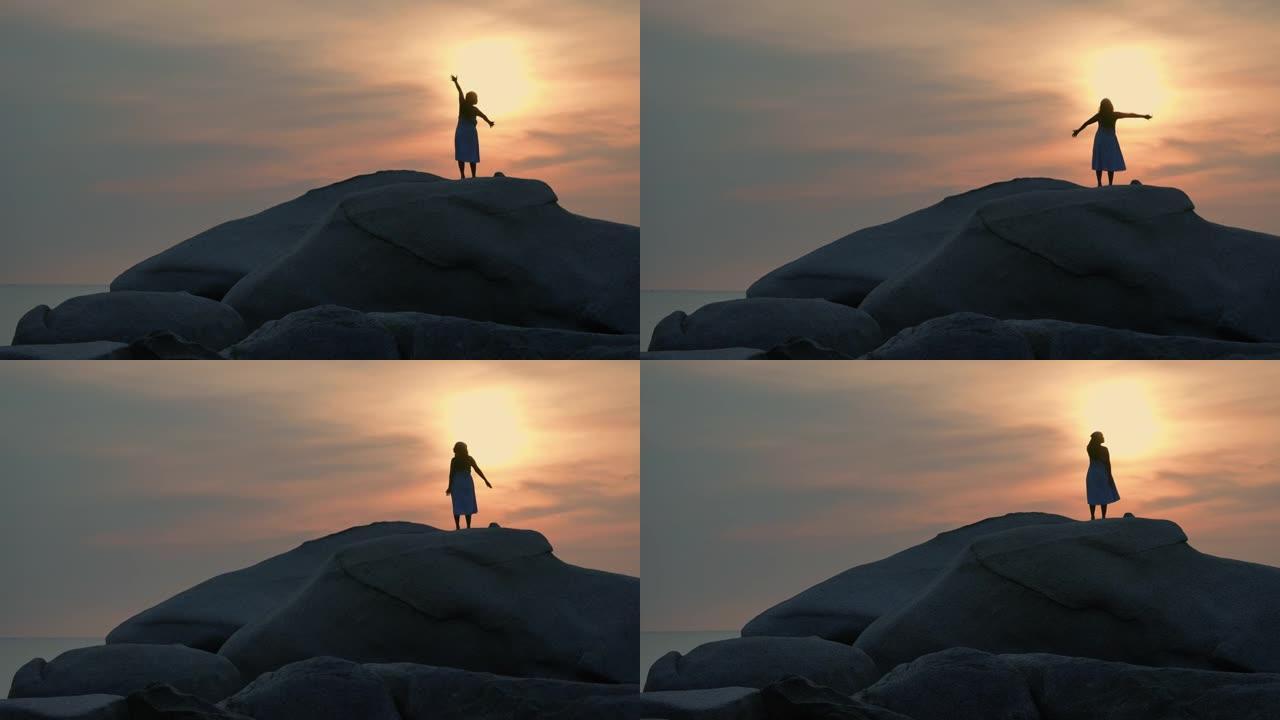 日落时站在山顶上的女人的剪影