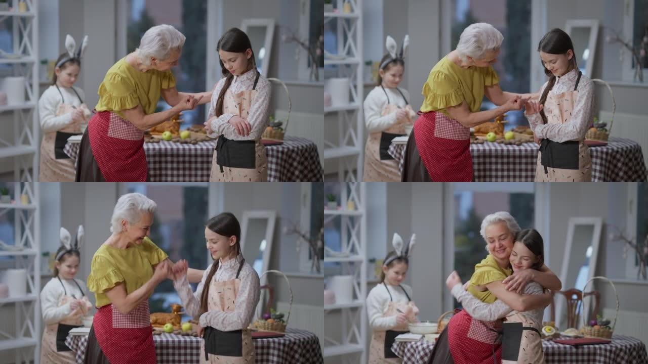 慈爱的高加索祖母与悲伤的十几岁的孙女和平相处，并发誓。微笑的女人和女孩在复活节星期天站在厨房里拥抱。