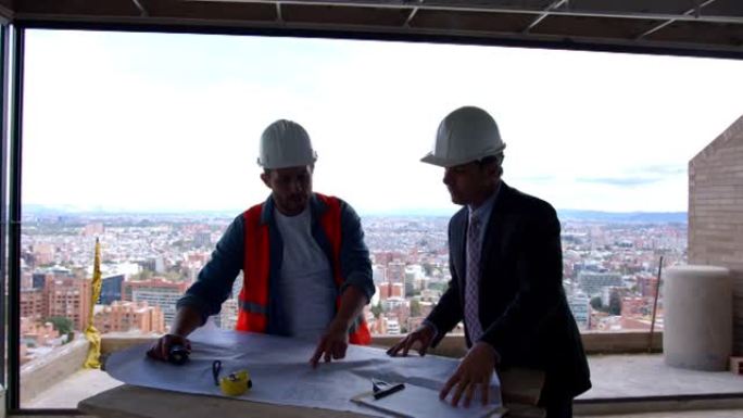 拉丁美洲的房地产开发商和建筑师在建筑工地上看着简易桌子上的蓝图