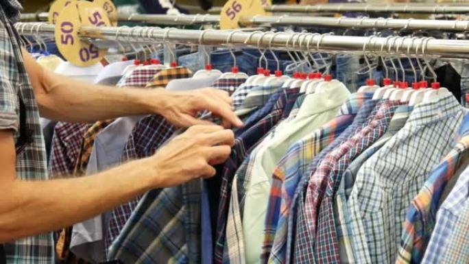 服装店货架上的一排方格衬衫，一位男性买家选择一件