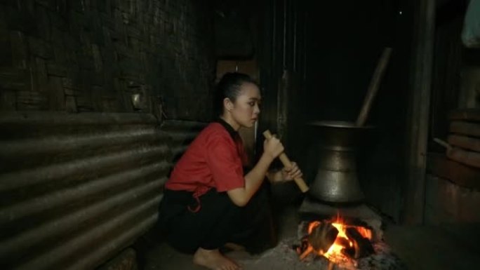 亚洲盲人妇女做饭时用一块竹制鼓风机吹老式火炉
