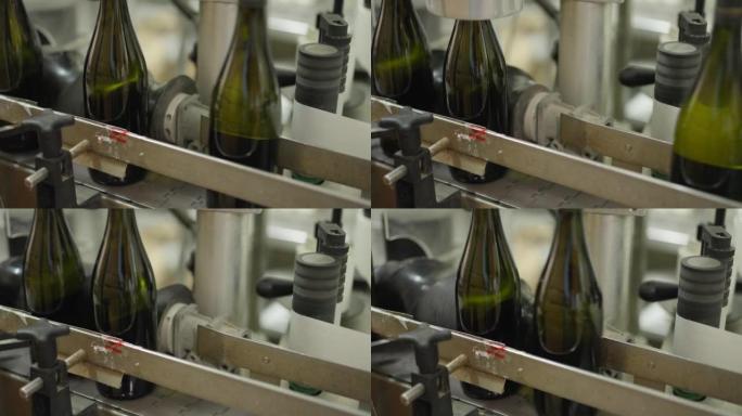 葡萄酒厂的近距离自动开瓶机，玻璃瓶通过。酒厂室内饮料包装和标签的过程。工业概念。