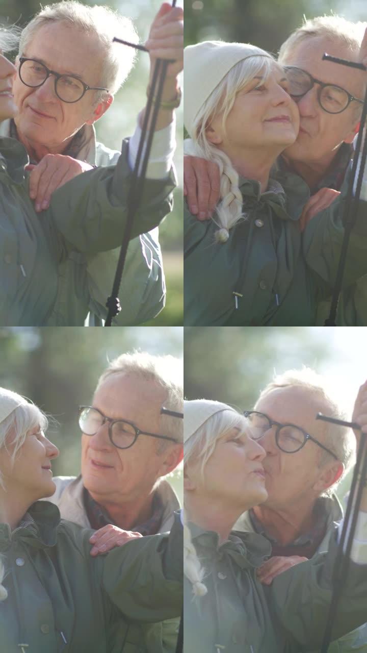 我爱你。特写老人推着妻子在公园的秋千上。丈夫亲吻妻子。垂直视频