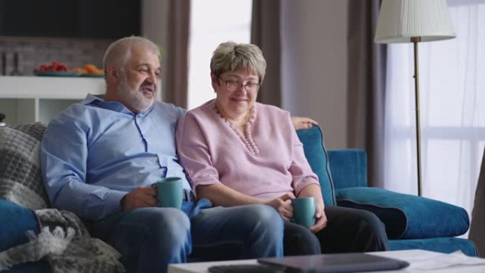 老人和女人在周末共度时光，坐在客厅的沙发上，愉快地聊天