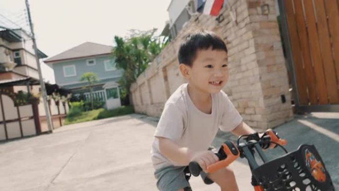 微笑的蹒跚学步的男孩在户外骑自行车
