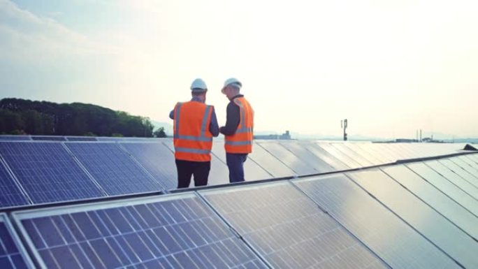 两名男工程师在太阳能发电厂的屋顶上进行讨论