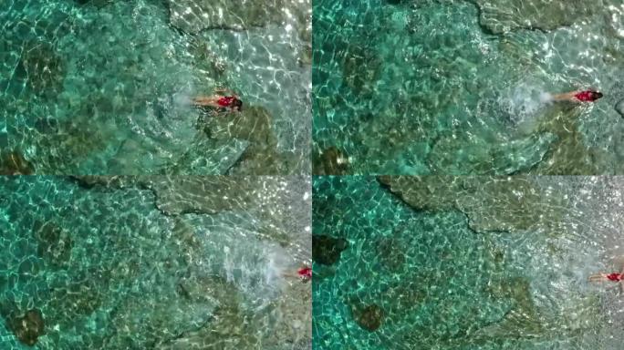 空中无人机拍摄了一名在海岸线附近游泳的妇女
