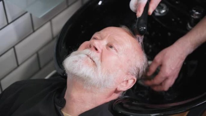 自我护理，一位老人在理发店里坐在理发椅上洗头