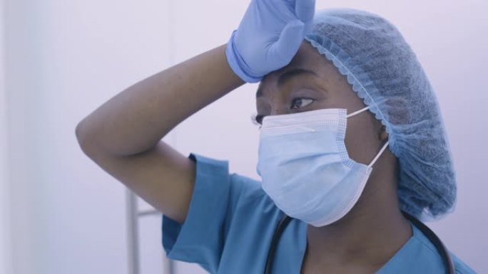 疲倦的非洲裔美国医生擦拭出汗的额头，疲惫，压力