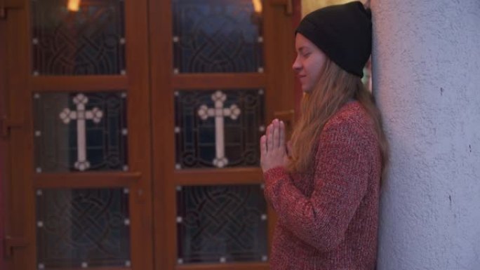 在教堂外祈祷的年轻女子
