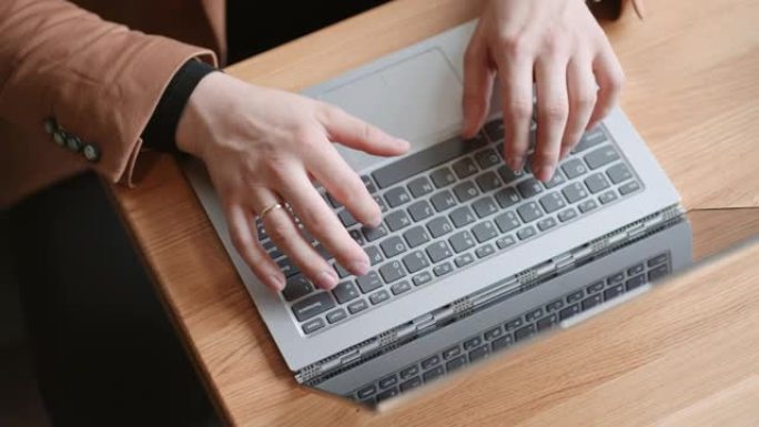 自由职业者或办公室工作人员正在办公室的笔记本电脑键盘上打字，从顶部特写视图