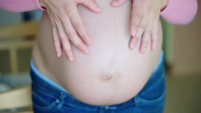 女人用手抚摸怀孕的肚子，用手指显示心形