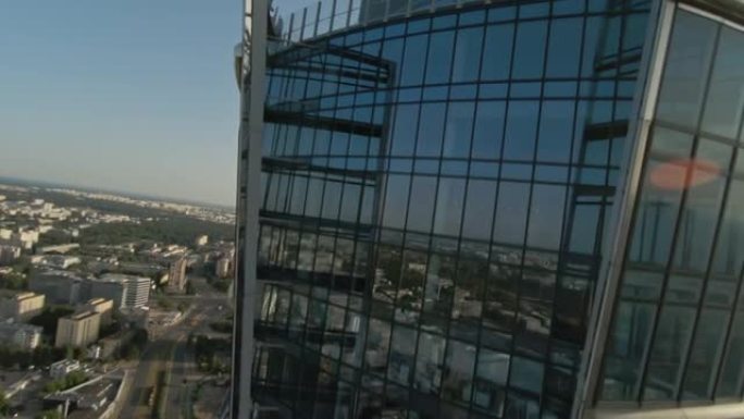 映照蓝天的玻璃摩天大楼。FPV无人机向建筑物移动