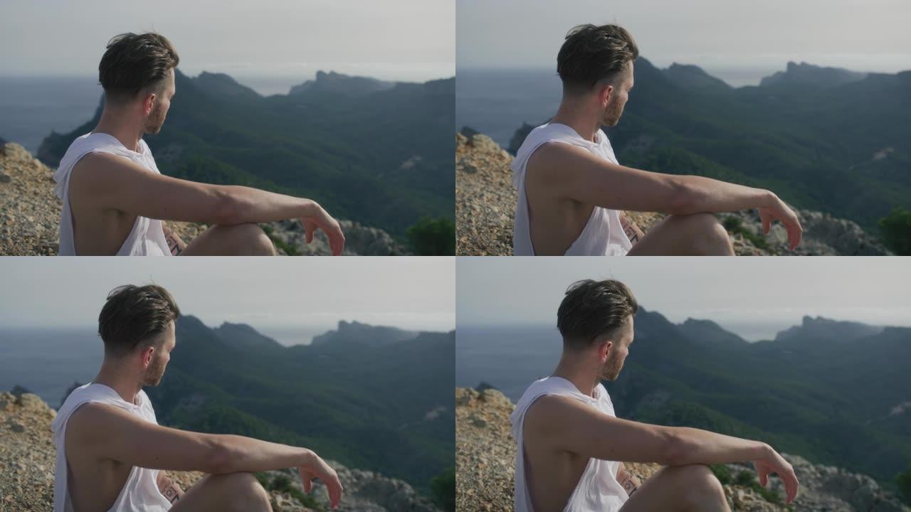 男人在山顶上放松，看着令人叹为观止的景色