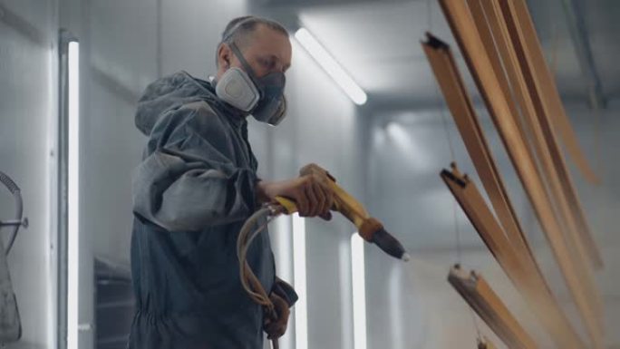 一个戴着呼吸器的人正在用粉末法涂金属。钢铁和金属结构的生产。画店。画家用喷枪涂漆作品