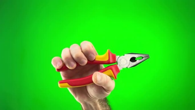 用红色和黄色手柄的钳子在绿色的chromakey背景下在人的手中必要的手工工具。修理工拿着钳子的手的