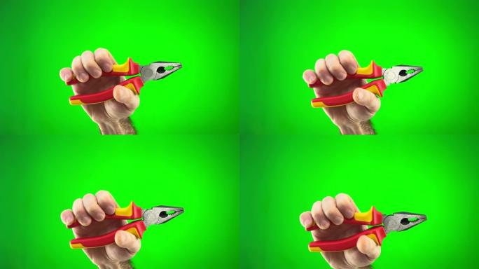 用红色和黄色手柄的钳子在绿色的chromakey背景下在人的手中必要的手工工具。修理工拿着钳子的手的