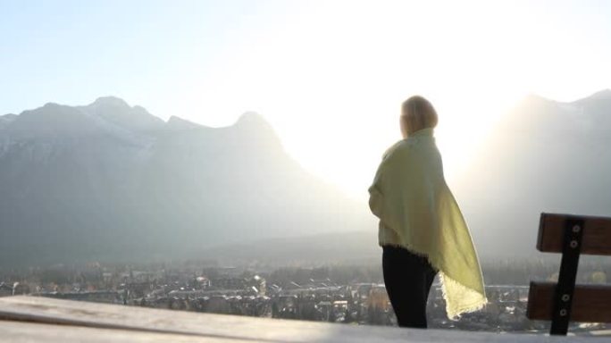 女人在披肩下停下来看日落，遥远的山脉
