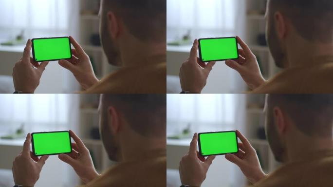 男人在手机的绿屏上观看，水平拿着，现代的小工具和用于教育，交流和娱乐的应用程序