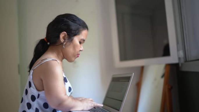 患有侏儒症的妇女在家中使用笔记本电脑工作或学习