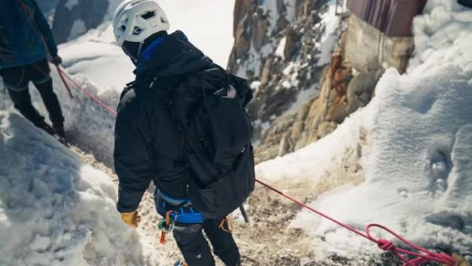 一队登山者连续攀登高峰。冬季冒险。视点