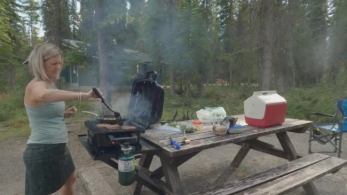一名妇女在荒野营地做饭的动态镜头