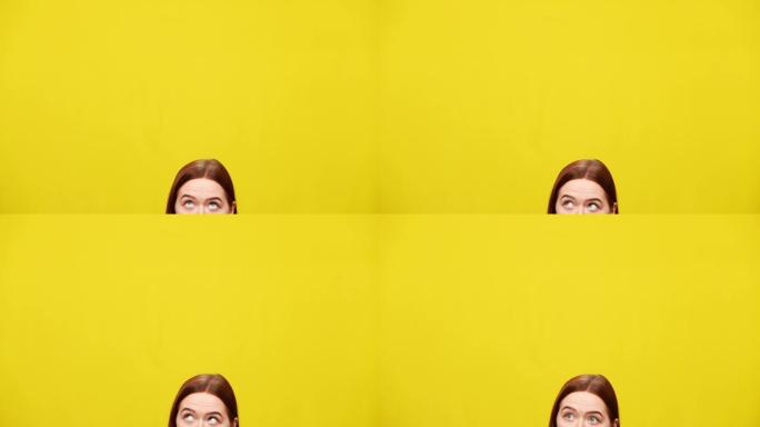 黄色背景下年轻红发女人的头顶。苗条的白人妇女的眼睛抬头看着彩色模型。广告概念。