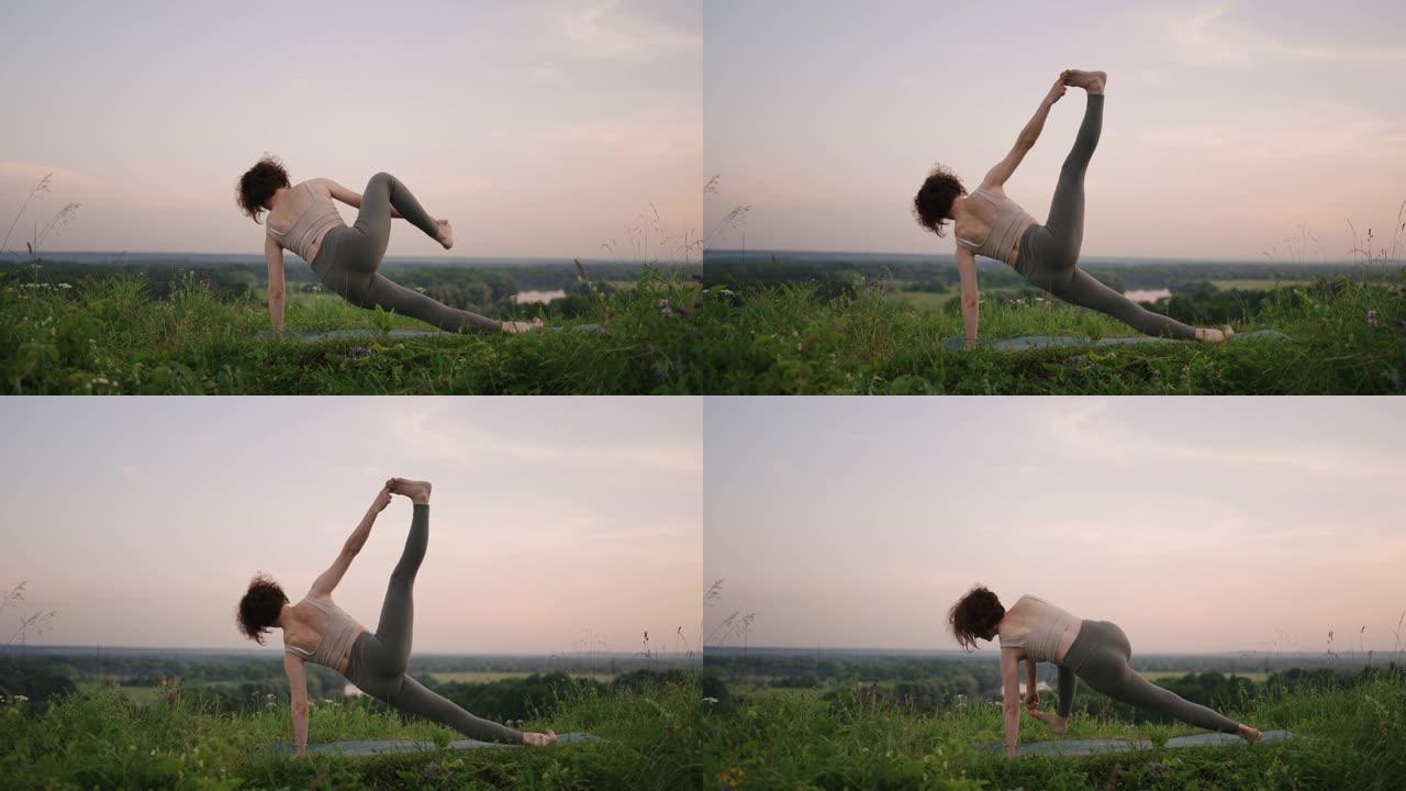 瑜伽大师做平衡和伸展运动。在森林中的山区做瑜伽的女孩的动作的和平与顺畅