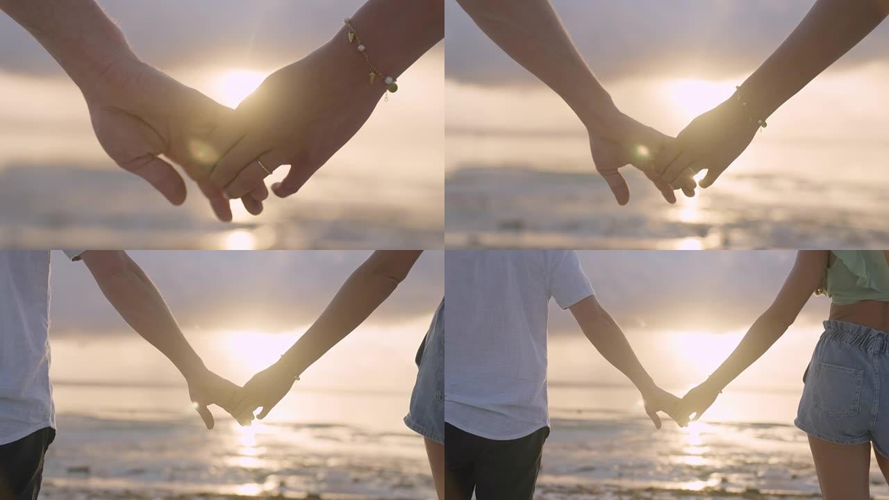 手牵手的夫妇。日落海滩上紫色和橙色天空的轮廓。