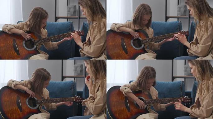 小女孩手里拿着吉他，正在学习演奏，母亲正在教书，并帮助她的女儿