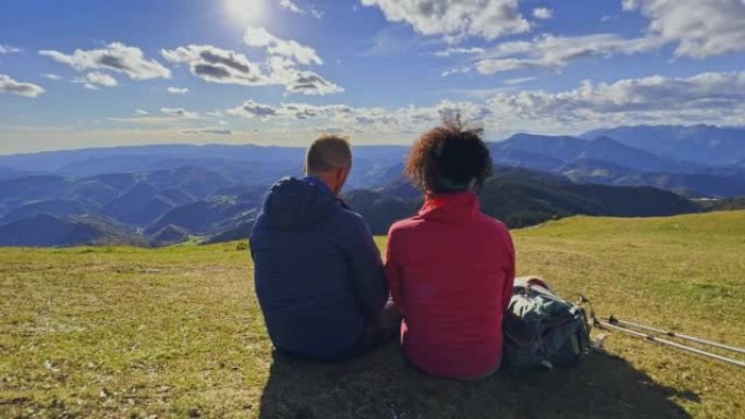 徒步旅行和放松后，SLO MO夫妇坐在阳光明媚的山顶上