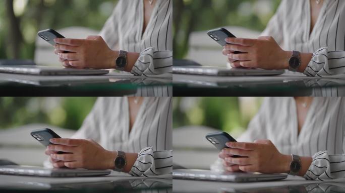 一个女人坐在夏季咖啡馆里在手机屏幕上打字的特写镜头。网上银行，浏览移动网站