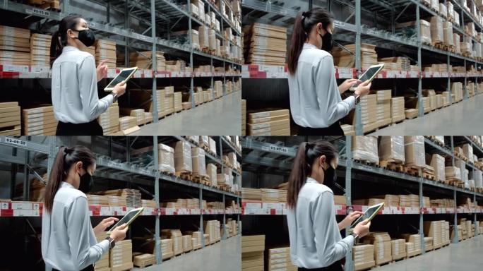 亚洲女性使用平板电脑在仓库中进行检查工作。