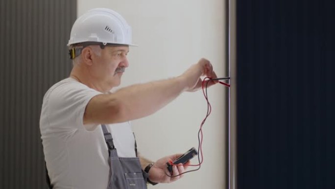 老年电工在安装和维修后使用现代房屋系统检查灯具墙壁控制单元的操作