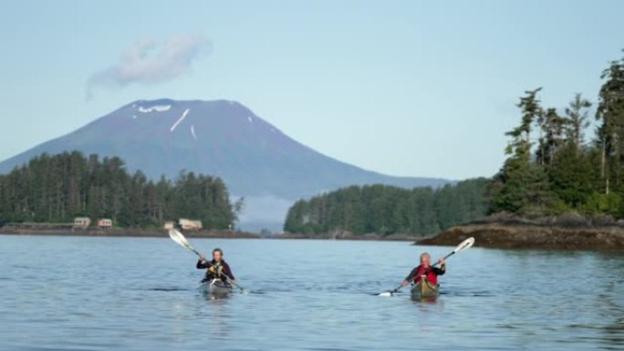 两名年长的皮划艇运动员在火山后面的河上划桨