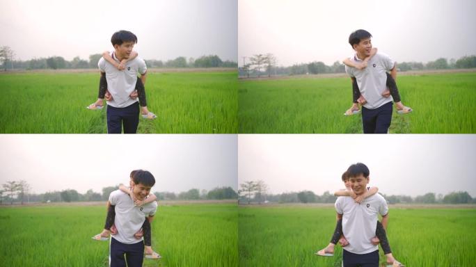 亚洲父女快乐快乐地走在绿色的田野里。