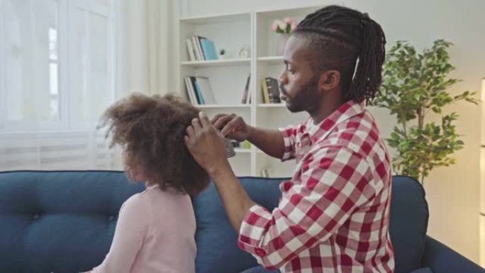 有爱心的非洲父亲梳理小女儿的卷曲头发，育儿时间