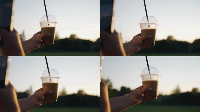 女孩手里拿着一杯咖啡，给它拍照。她在日落时拍照