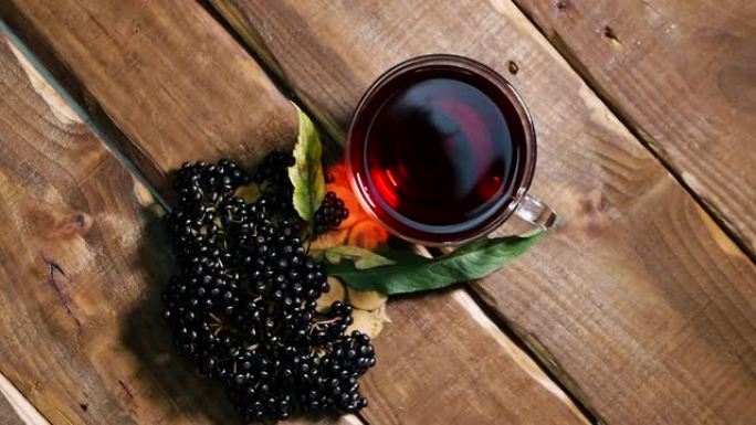 顶视图天然红莓茶在一个玻璃杯上的古董木桌。黑接骨木浆果中的浆果茶。从浆果接骨木中挤出的顺势疗法汁。