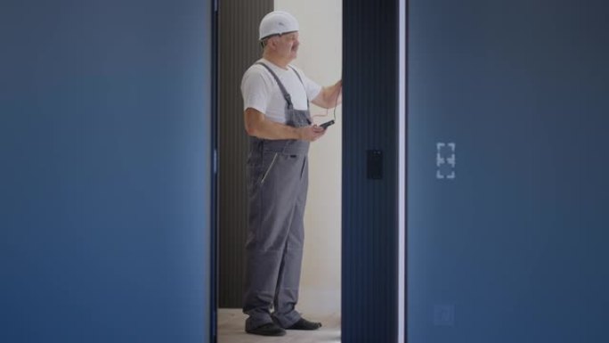 电工在安装和维修后使用现代房屋系统检查灯具墙壁控制单元的操作