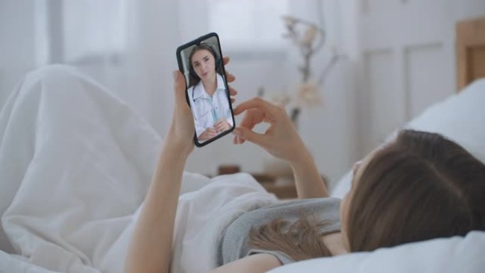女性使用在线聊天与家庭治疗师交谈，并检查冠状病毒大流行期间可能的症状。女人在智能手机上使用医疗应用程