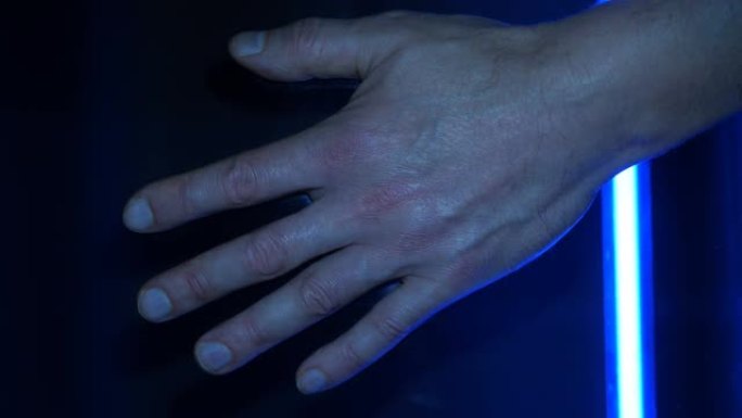 移动扫描仪灯的蓝色照明被扫描到男性手掌