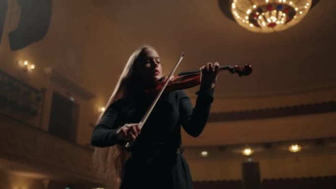 年轻的女音乐家在老歌剧院的现场摆弄，美丽的小提琴手正在拉小提琴