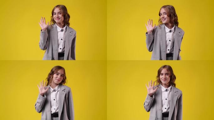 黄色背景上可爱的女孩挥手打招呼的4k慢动作视频。