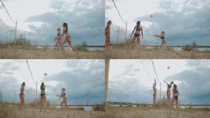 年轻的运动型女性在夏日在露天的桑迪球场上打沙滩排球，球员们在传球，进攻和盖球。